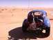 1970 Volkswagen Beetle - A blue Volkswagen Beetle dune buggy is seen from the rear, parked on a sand dune under a clear sky.