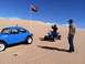 1970 Volkswagen Beetle - A blue Volkswagen Beetle and a blue ATV are parked in the sand dunes under a clear blue sky.