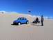 1970 Volkswagen Beetle - A blue 1970 Volkswagen Beetle and an ATV sit on sand dunes with two people nearby.