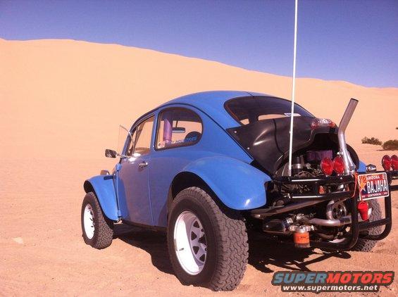 Blue 1970 Volkswagen Beetle Baja Bug with off-road tires and exposed engine in desert landscape