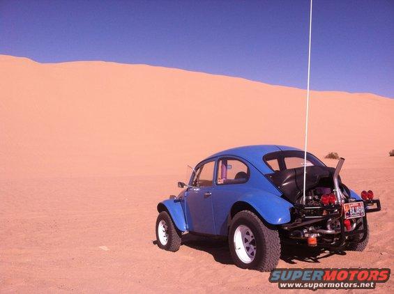 Blue 1970 Volkswagen Beetle Baja Bug with exposed engine and roll cage in desert