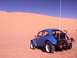 1970 Volkswagen Beetle - A blue 1970 Volkswagen Beetle modified for off-road use, known as a Baja Bug, parked in a sandy desert landscape under a clear blue sky.