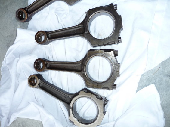 Four engine connecting rods laid out on a white cloth
