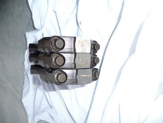 Three engine connecting rods stacked on white cloth