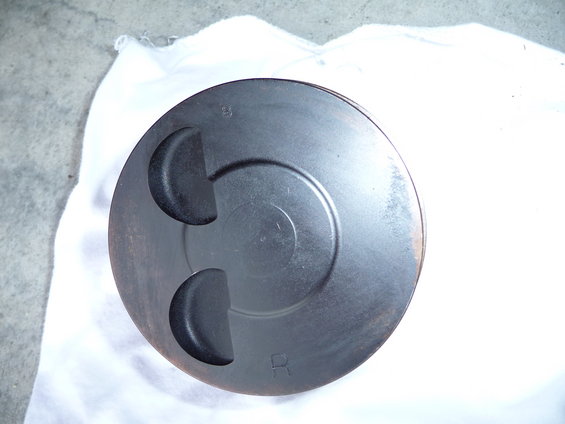 Engine piston with two valve reliefs and circular markings. 'B' and 'R' are visible