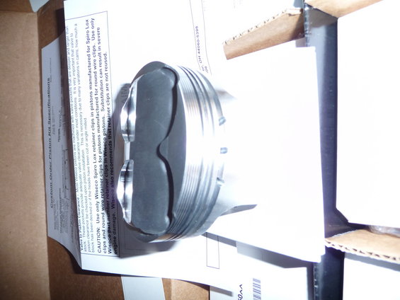 Wiseco piston with two valve reliefs, sitting on a document with specifications