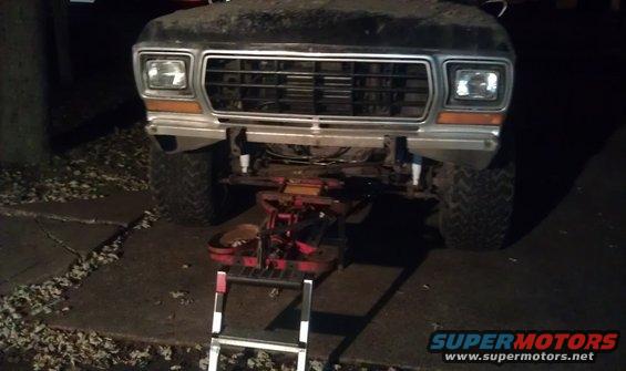 1979 Ford Bronco front grille and bumper with a red creeper seat in front