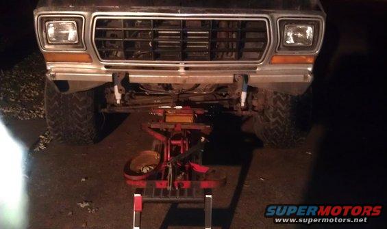Front end of a truck, grille and headlights visible. It's on a jack with some mechanical parts underneath