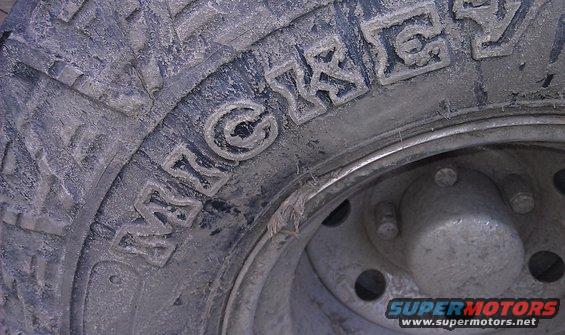 Close-up of a dirty tire with 'MICKEY' visible in raised letters. The wheel hub is also visible