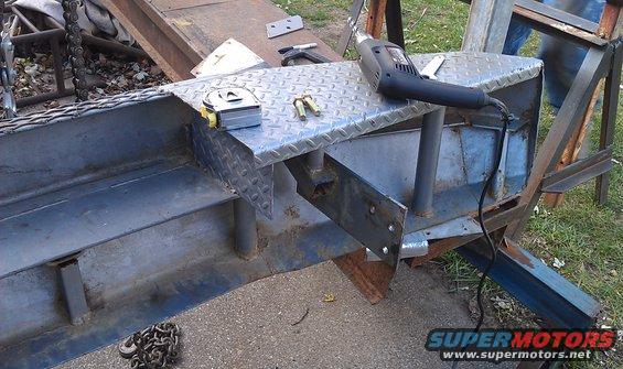 Metal fabrication project with a tape measure, bolts, and a heat gun on a diamond plate surface