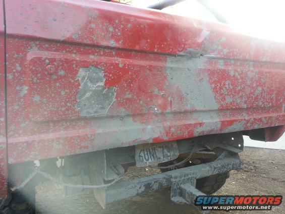 Red SUV rear quarter panel covered in mud, with a license plate reading 6UNL759