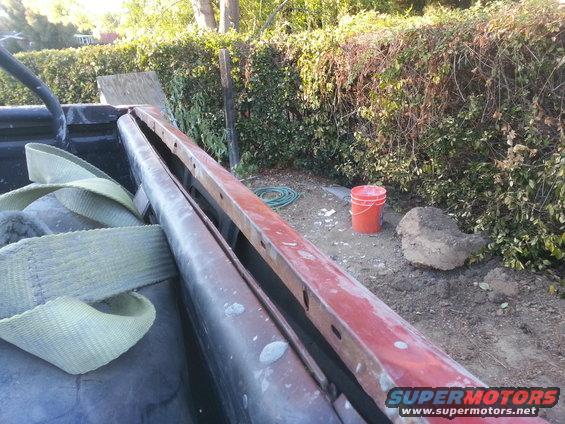 Truck bed interior with straps and a red metal bar