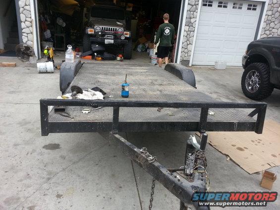 Flatbed trailer in front of garage with a Jeep and a pickup truck visible