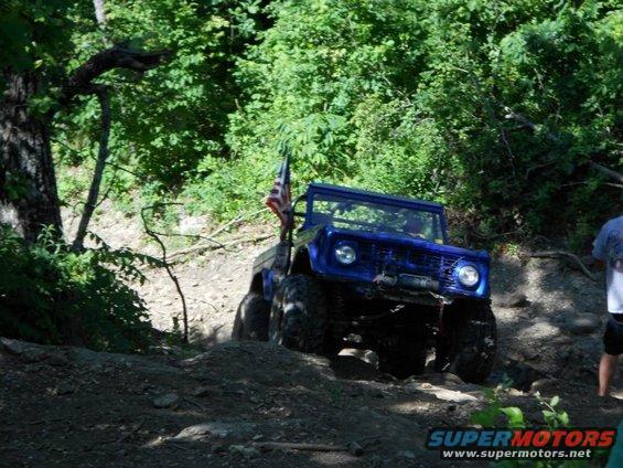 Blue off-road vehicle with an American flag, climbing a dirt hill