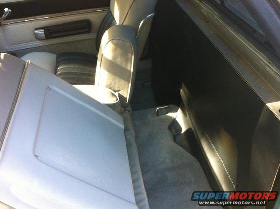 Car interior with light gray seats and dark gray carpet, showing the back of the front seats and the rear passenger area