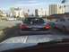 2003 Ford Crown Victoria - A Mercury Grand Marquis is seen from behind at a traffic light, with other vehicles and buildings in the background.