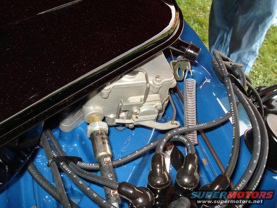 Close-up of a carburetor with spark plug wires attached to a blue engine block