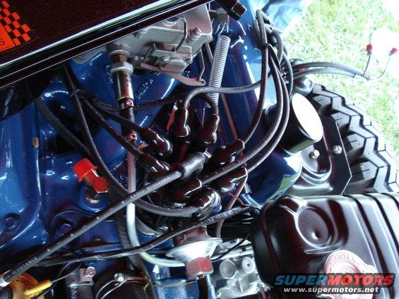 Close-up of a blue engine bay showing spark plug wires, distributor, and part of a tire