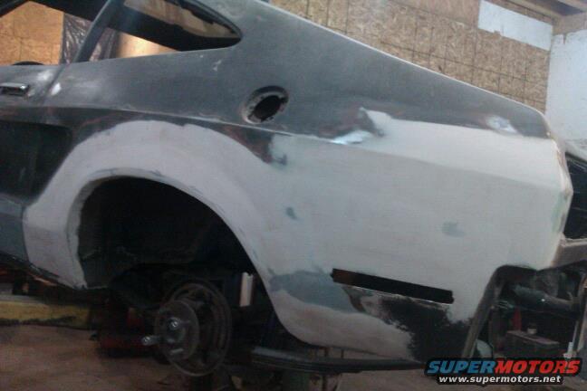 car's rear quarter panel being worked on, primer and body filler visible
