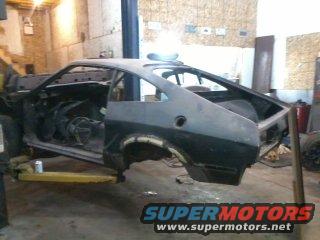 Car body being worked on in a garage, missing doors and interior