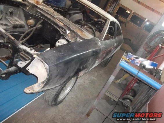 Car body in disrepair, primer gray, front quarter panel removed, 3q-front view