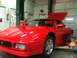 1990 Ford Bronco - Red Ferrari convertible on a lift in a garage with the hood open.