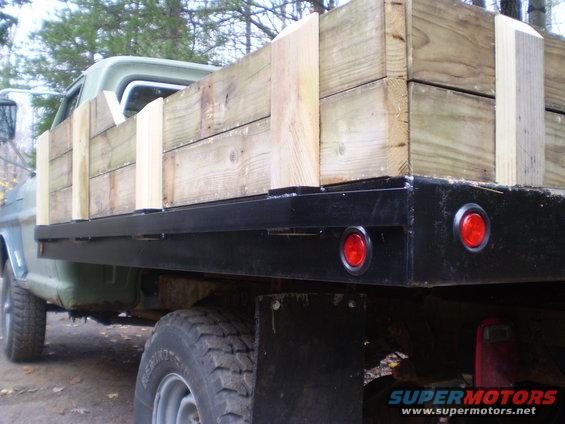 Flatbed truck side view with wooden cargo and red taillights