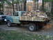 1979 Ford Bronco - A vintage Ford flatbed truck, likely from the 1970s, is seen from the side, heavily laden with cut firewood.