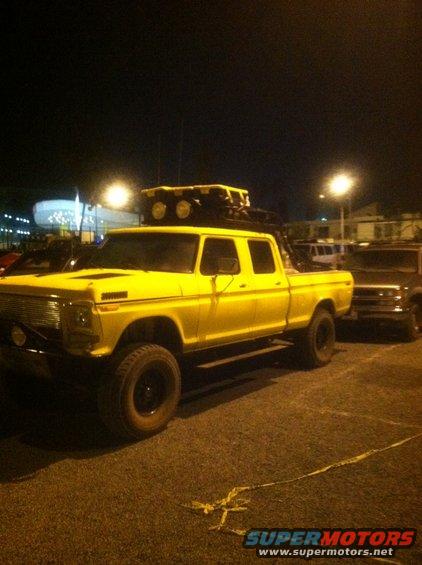 Yellow crew cab pickup truck with roof rack and off-road tires