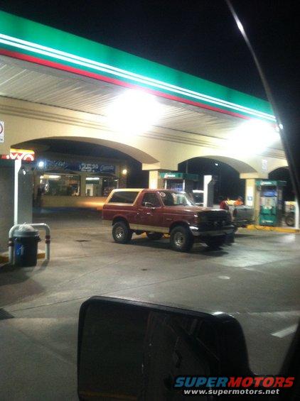 Red and tan SUV parked at a gas station at night. The vehicle has a removable top
