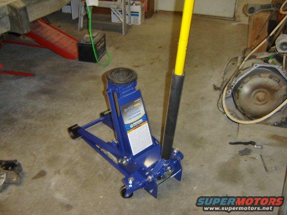 Blue hydraulic floor jack with yellow handle in a garage