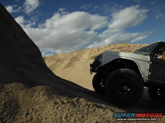 White off-road vehicle with large tires on a sandy incline