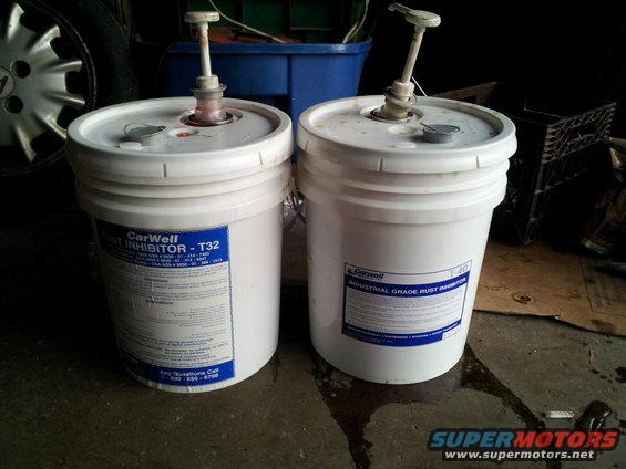 Two white 5-gallon buckets with pumps, one labeled CarWell Rust Inhibitor - T32