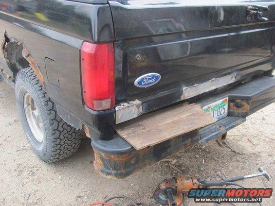 1996 Ford Bronco rear with rust damage and a wooden step