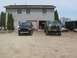 1996 Ford Bronco - Two SUVs are parked in front of a building with two garage doors.