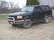 1996 Ford Bronco - A black 1996 Ford Bronco is parked outdoors on a dirt surface, showing its side and front quarter view.
