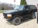 1996 Ford Bronco - This black Ford Bronco shows significant rust damage on its body panels.