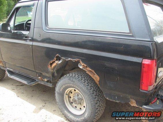 Black 1996 Ford Bronco side view showing severe rust on rear fender and rocker panel
