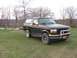 1996 Ford Bronco - A black Ford Bronco is parked on a grassy field with bare trees in the background.
