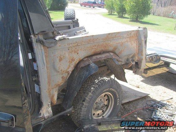 rusted truck bed and fender with visible tire and wheel