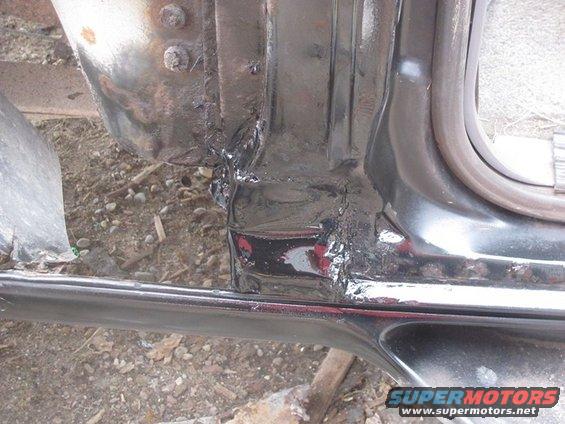 Close-up of rusty metal and black paint on a vehicle's lower body panel