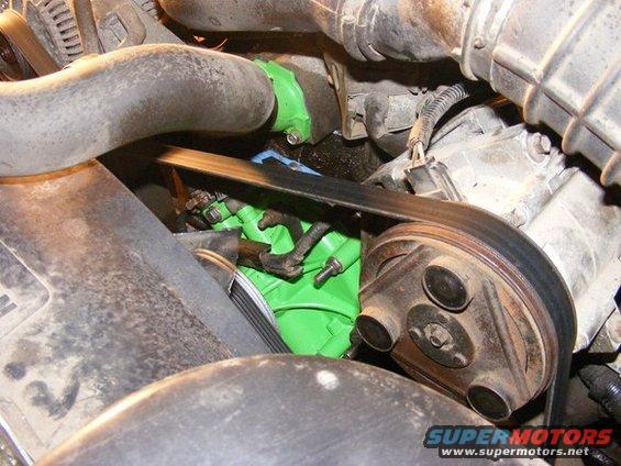 Engine bay with green painted component, serpentine belt, and pulley