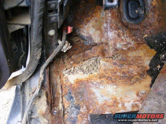 rusted floor pan area with visible wiring and conduit