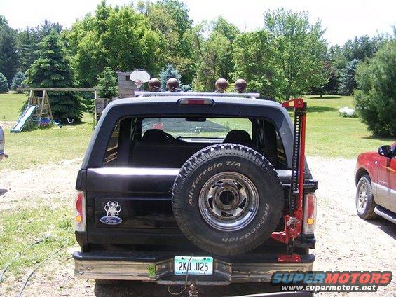 Black 1996 Ford Bronco rear view with spare tire mounted on the back and a high-lift jack attached to the side