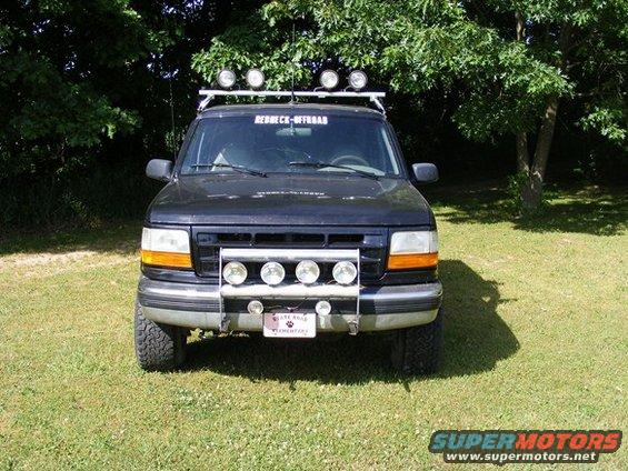 Black Ford Bronco with roof rack and front bumper lights parked on grass