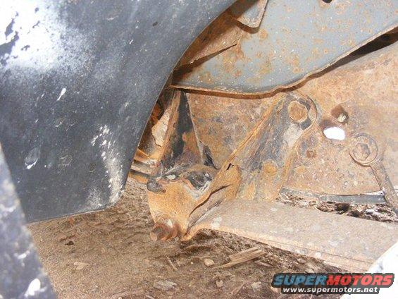 Rusted suspension parts under a vehicle, showing significant corrosion