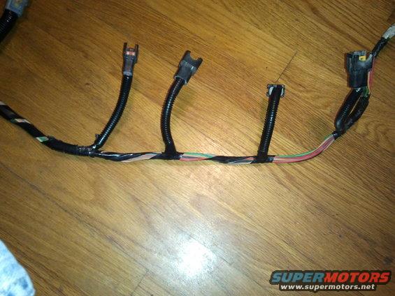 Automotive wiring harness with multiple connectors and colored wires on a wooden surface