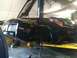 1990 Ford Bronco - Black sports car on a lift in a garage, undergoing maintenance. The front wheel is off.