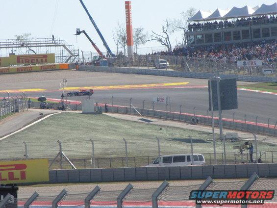 White limousine parked on a race track with spectators in the background
