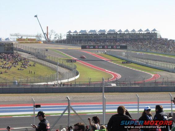 Red race car on a track with grandstands and spectators